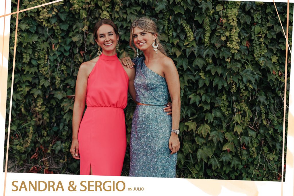 Foto de dos invitadas de una boda posando en un jardín